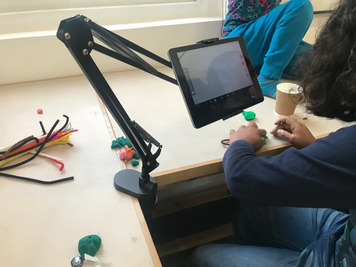 An individual is playing with plasticine and filming the pieces as they move them around a table.